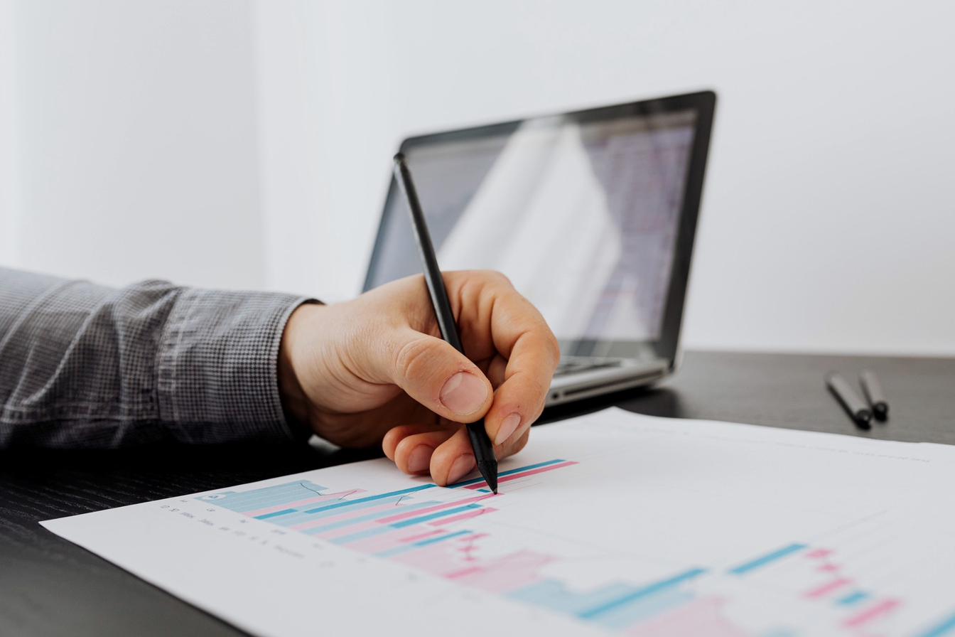 A researcher annotating a printed trend while comparing it with digital context